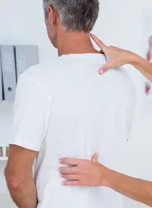 chiropractor looking at male patients back 
