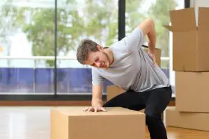 man holding his lower back after lifting a heavy box.