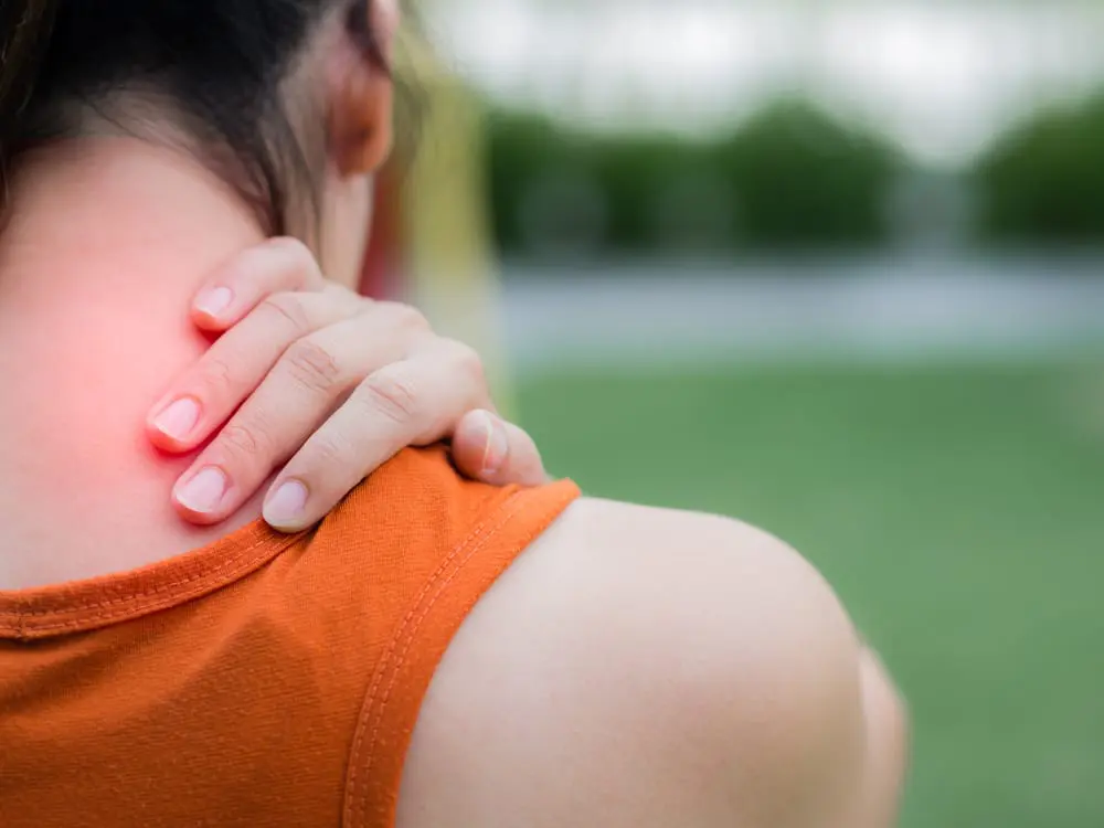 woman holding her upper back due to pain