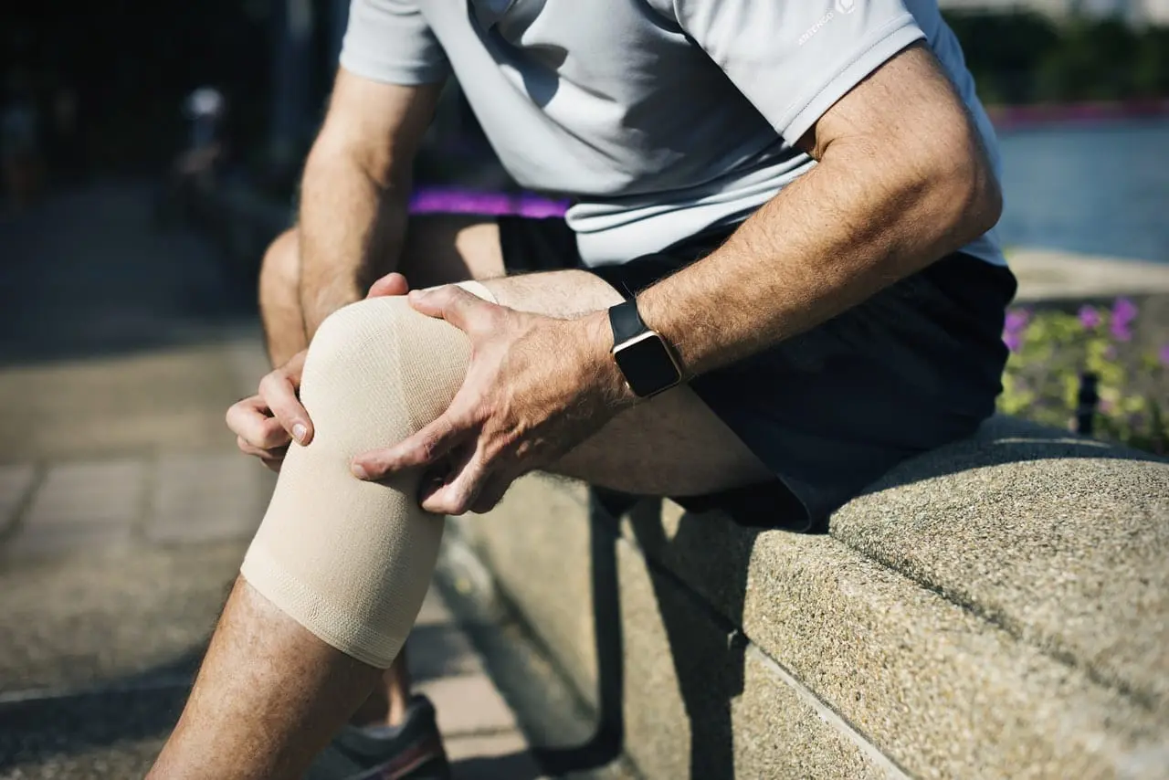 Sports Man holds knee seeking pain treatment in omaha