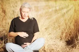 Pregnant Woman in Omaha field holds belly