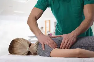 chiropractor adjusting female patients upper back