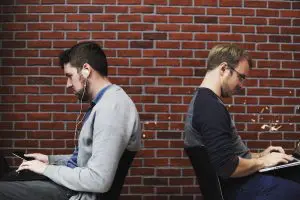 2 coworkers slouching over their laptops 