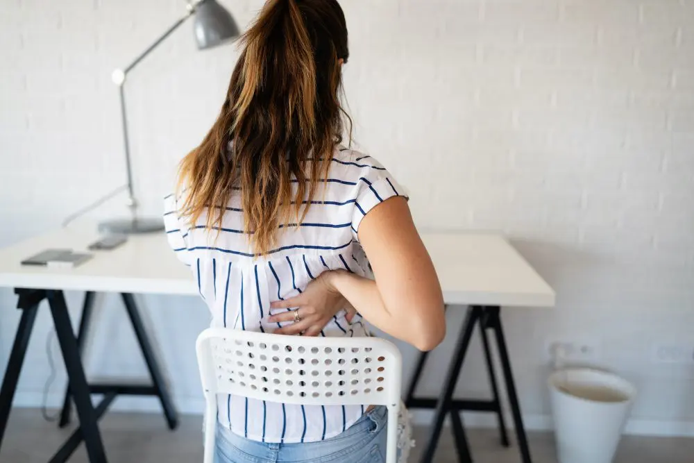 woman having back pain from sitting in her chair