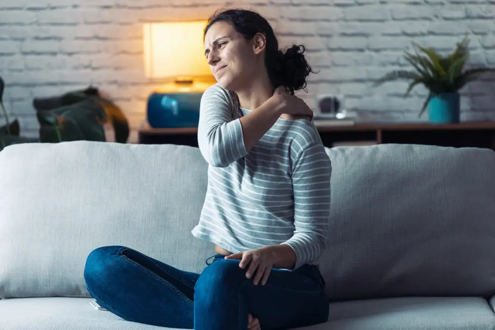 young woman holding her shoulder due to pain