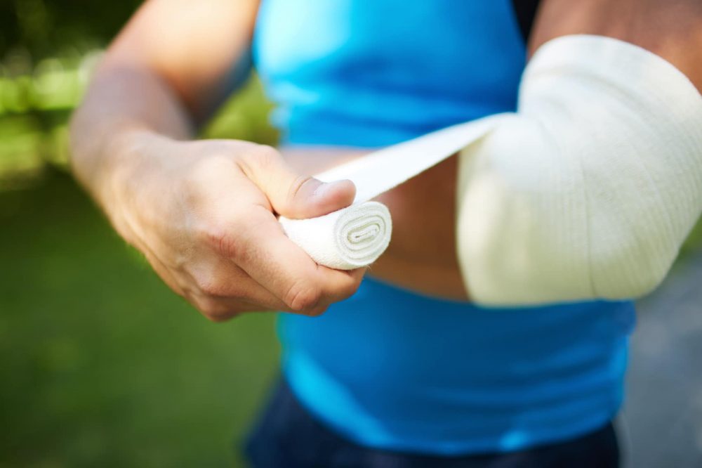 young man bandaging his elbow 