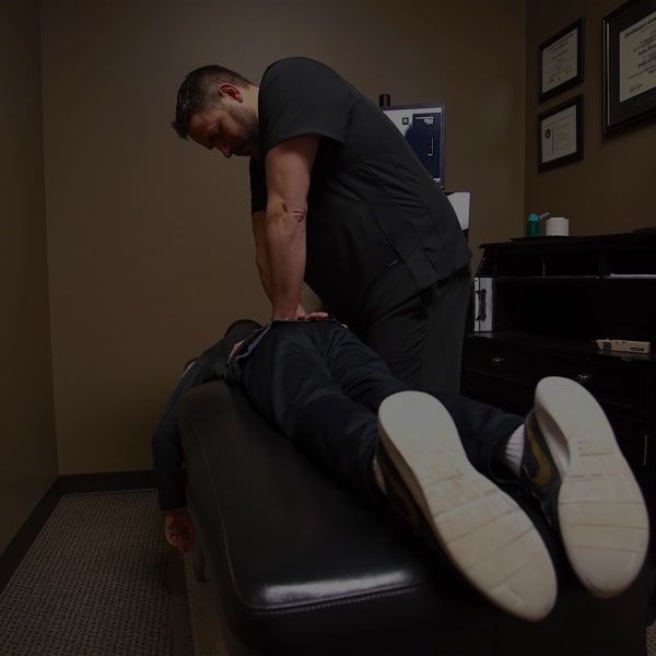 male chiropractor adjusting a patient's lower back on laying a drop table