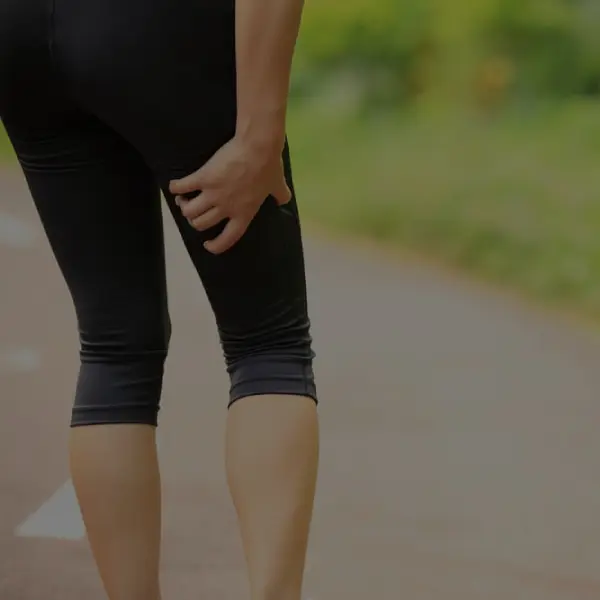 woman having sciatica pain on her leg while jogging