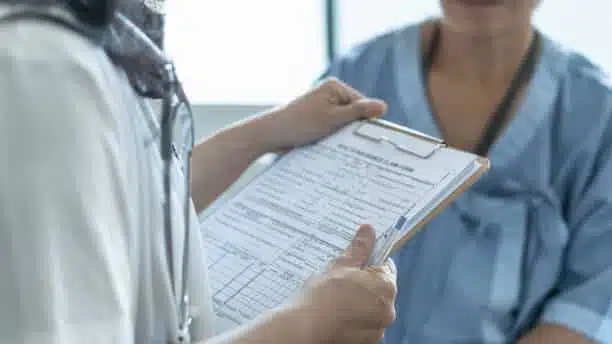 Patient health insurance claim form in doctor's hand for medical coverage and treatment.
