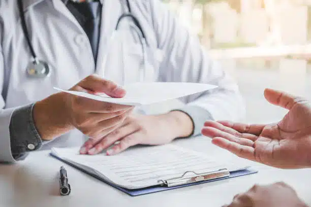 Chiropractor is handling the health insurance form to the patient.