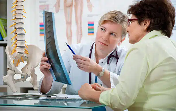 Chiropractor shows the problem areas on a X-ray to patient and  explains the cause of her pain.