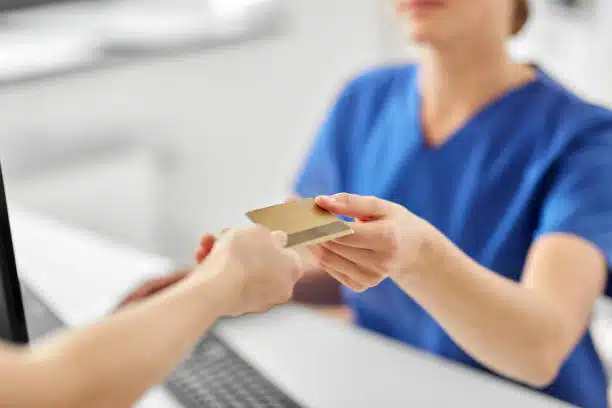 Billing attendant handling patient's card after paying with health insurance.