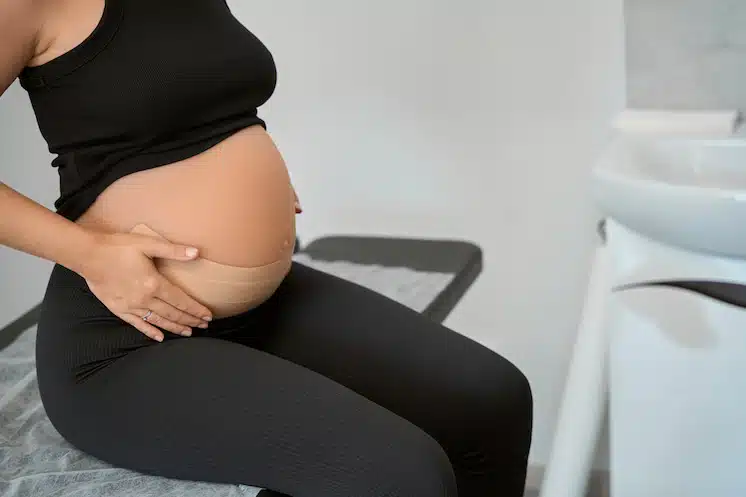 pregnant woman sitting on bed while waiting for chiropractor for Prenatal Chiropractic care in west omaha