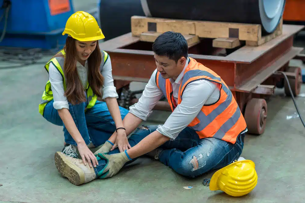 co-worker performing first aid to fellow worker experiencing work-related injury